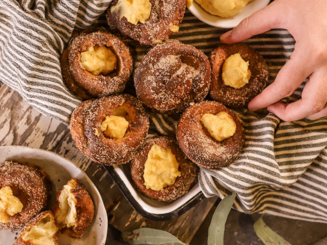 Hand taking a Cinnamon Sugar Popover with Creme Patisserie